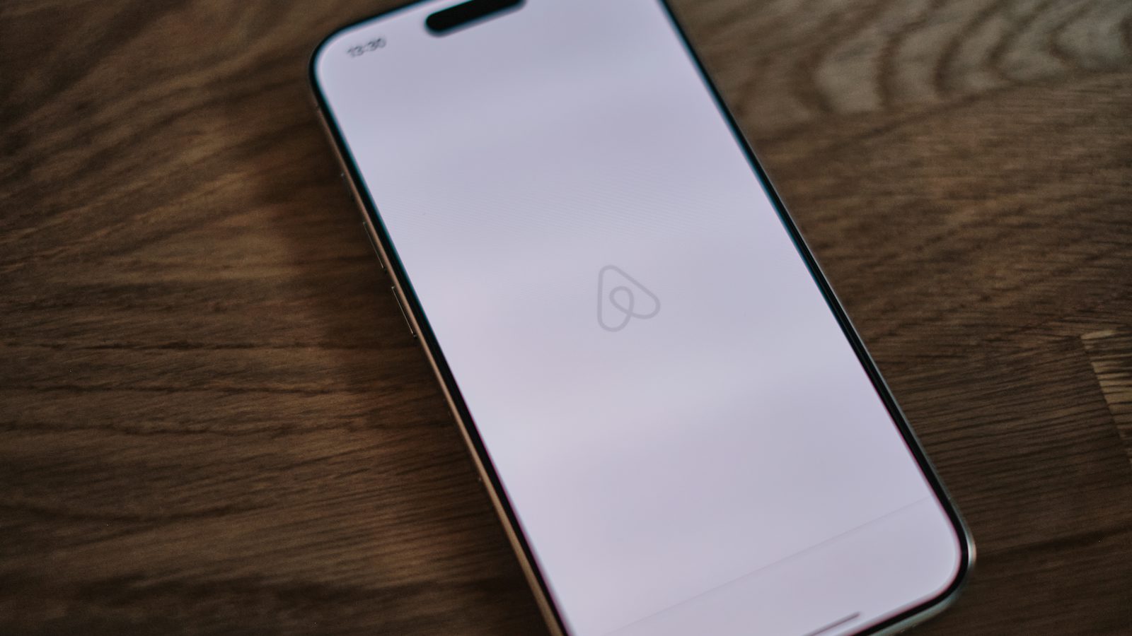 Celular com o aplicativo do Airbnb aberto sobre uma mesa de madeira